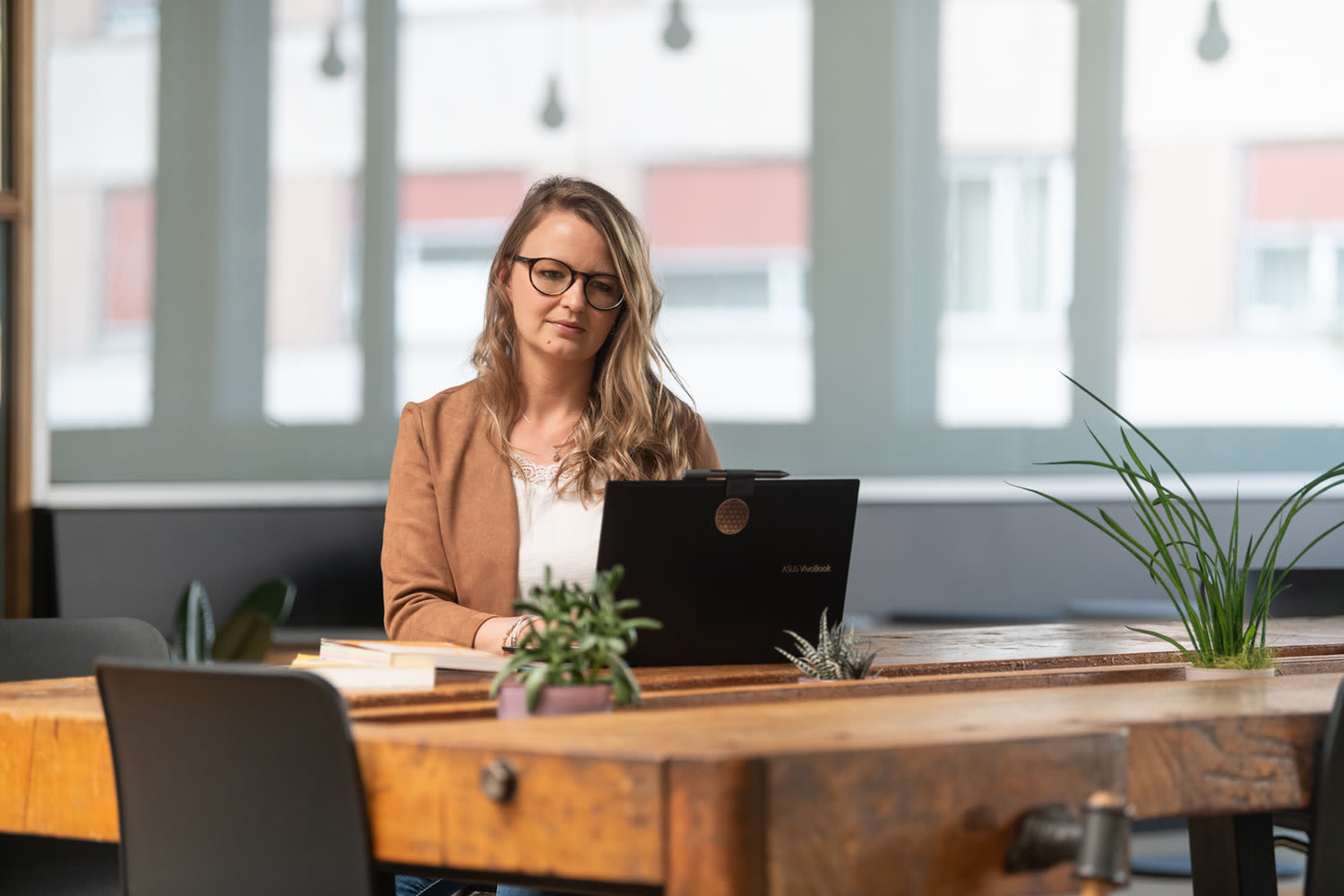 Sabrina Stöckli, Payroll-Spezialistin ad interim, arbeitet am Laptop an einem Holztisch